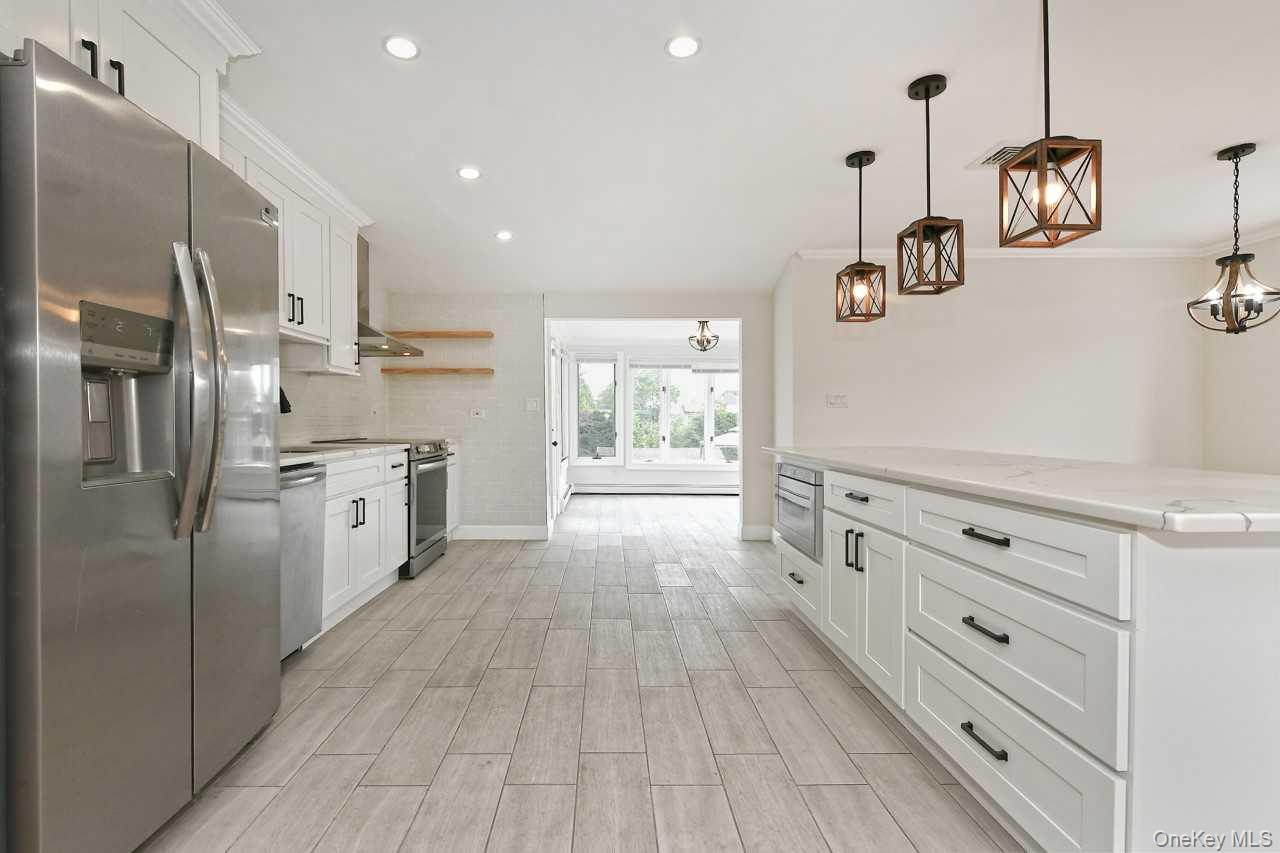 107 Beverly Road Massapequa, NY 11758 - Photo 13 of 41 a kitchen with white cabinets and stainless steel appliances