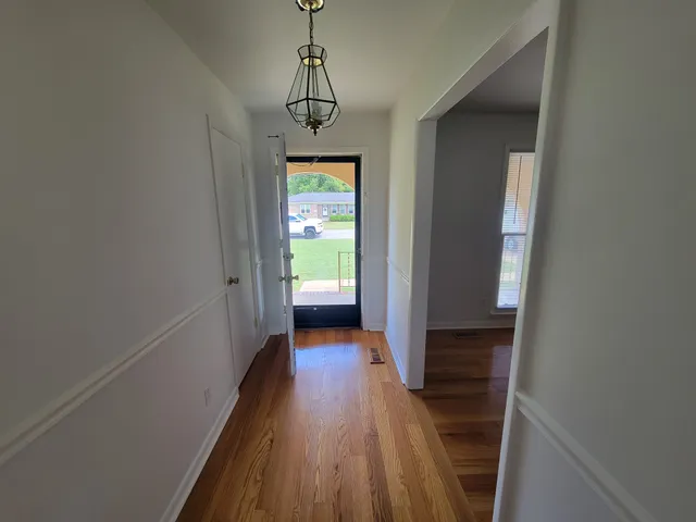 a view of a hallway with wooden floor and a bathroom