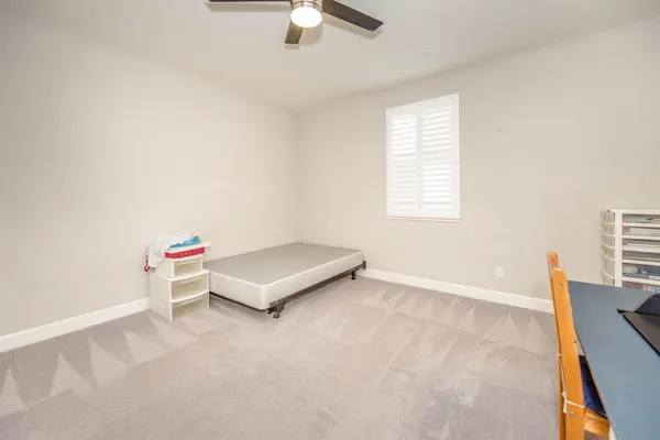 an empty room with ceiling fan and window