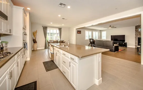a large white kitchen with stainless steel appliances a sink and a large window