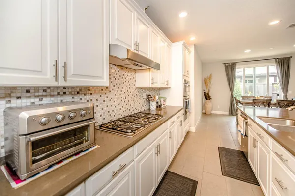 a kitchen with stainless steel appliances a stove a sink cabinets and a wooden floor
