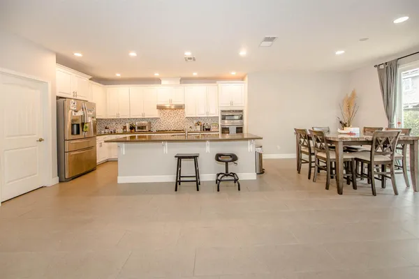 a kitchen with stainless steel appliances dining table a sink and a refrigerator