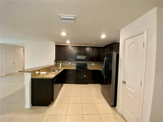 a kitchen with stainless steel appliances kitchen island granite countertop a refrigerator and a sink