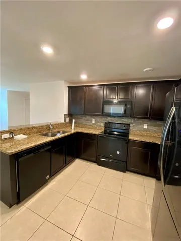 a large kitchen with granite countertop a stove sink and cabinets