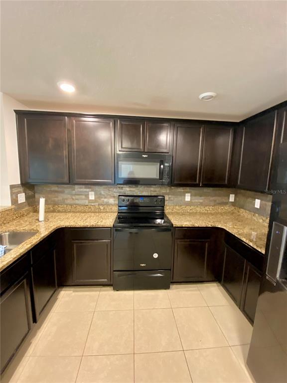 8659 Silverbell Loop Brooksville, FL 34613 - Photo 16 of 36 a large kitchen with granite countertop a stove sink and cabinets