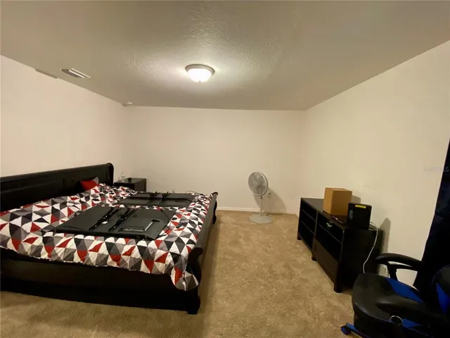 a bed sitting in a bedroom next to a window and a lamp