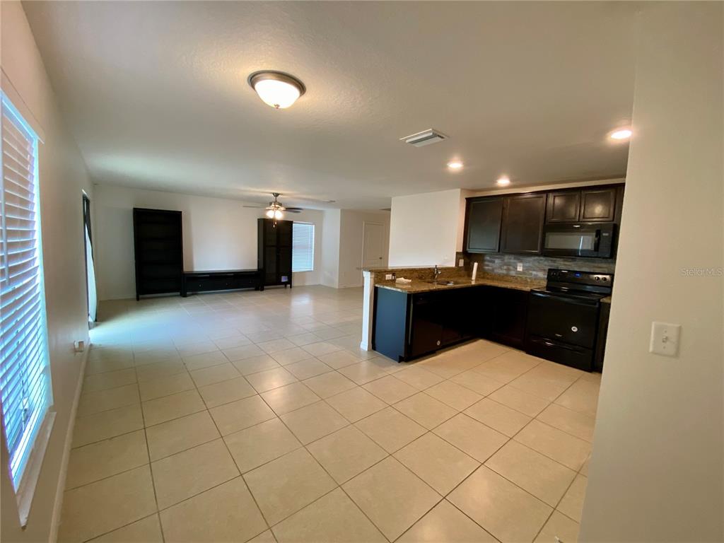 8659 Silverbell Loop Brooksville, FL 34613 - Photo 9 of 36 a kitchen with kitchen island granite countertop a sink and a refrigerator