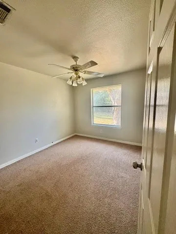 an empty room with windows and fan