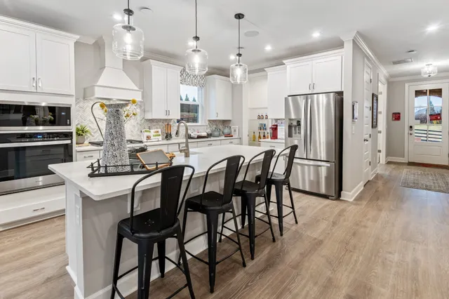 a kitchen with stainless steel appliances a dining table chairs stove refrigerator and cabinets