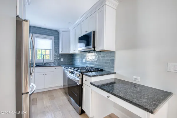 a kitchen with stainless steel appliances granite countertop a stove a sink and a microwave