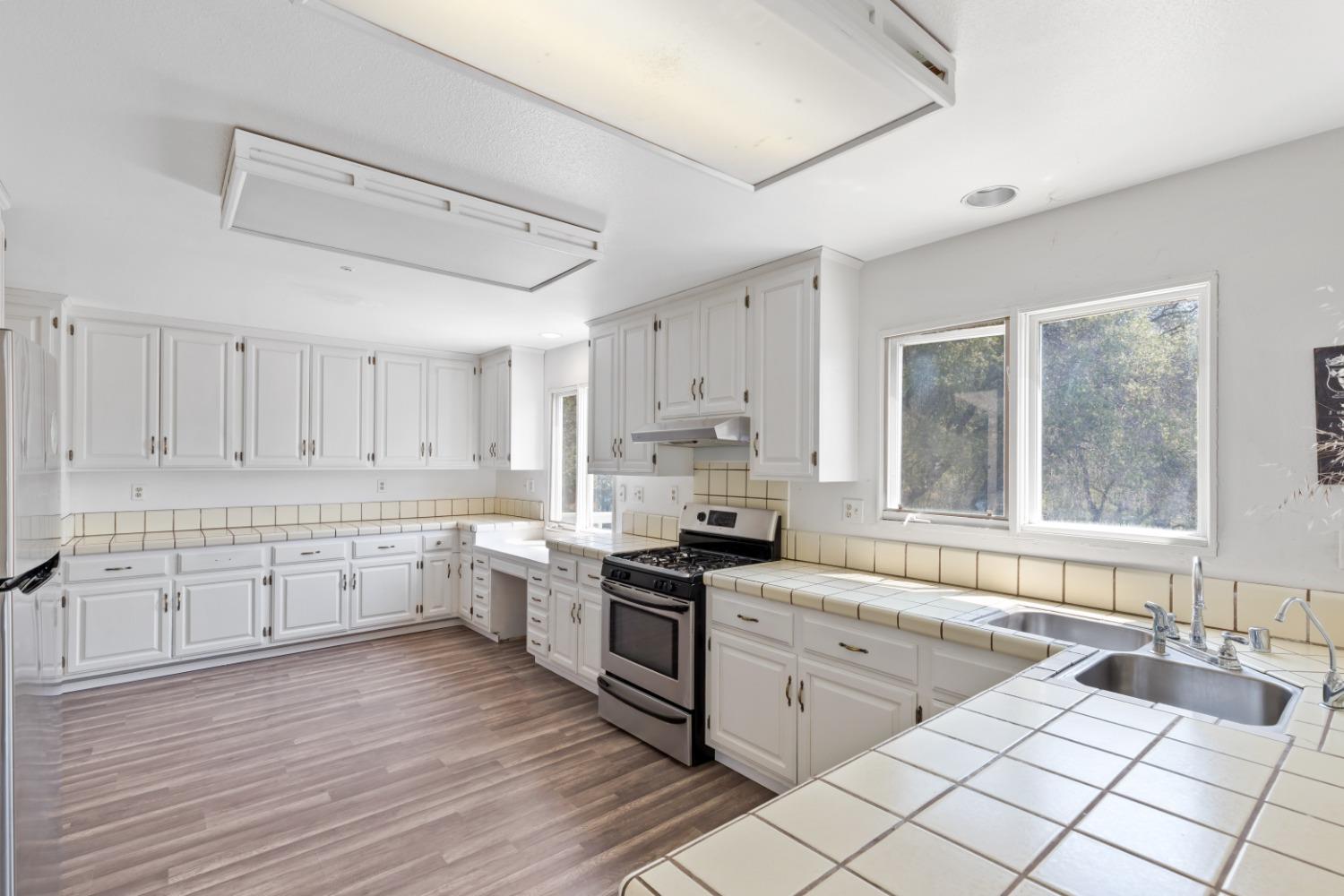 40707 Jean Road East Oakhurst, CA 93644 - Photo 8 of 44 a kitchen with granite countertop white cabinets white appliances a sink and a large window