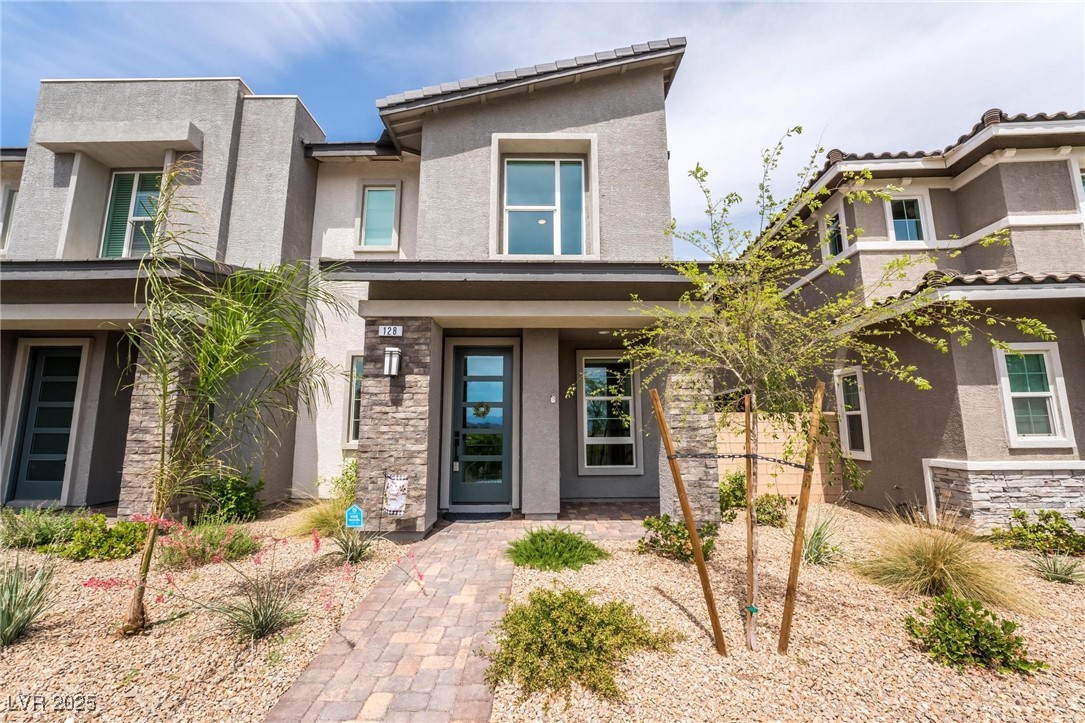 Entrance to property with stone siding, stucco siding, and covered porch
