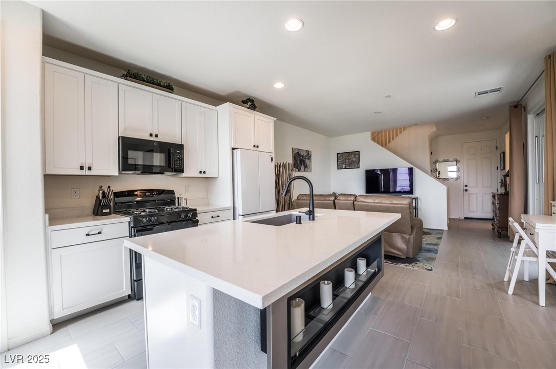 128 Kimberlite Drive Henderson, NV 89011 - Photo 12 of 55 Kitchen with gas stove, black microwave, a center island with sink, recessed lighting, and white cabinetry