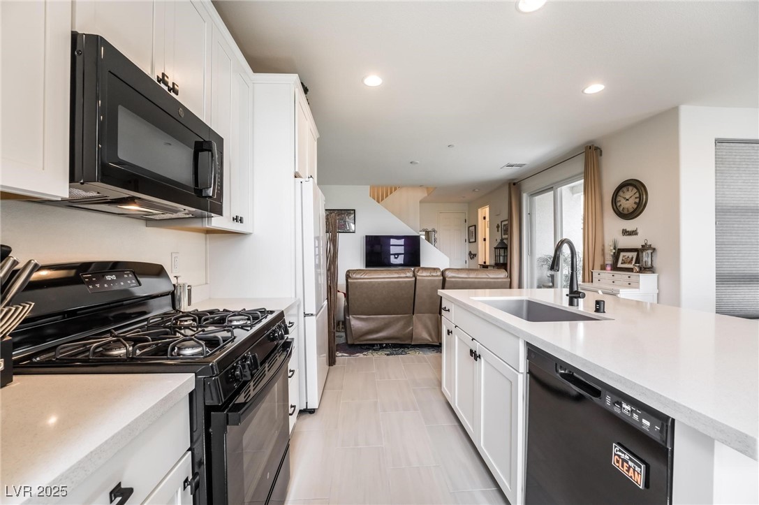 128 Kimberlite Drive Henderson, NV 89011 - Photo 55 of 55 Kitchen featuring black appliances, white cabinetry, open floor plan, recessed lighting, and light stone counters