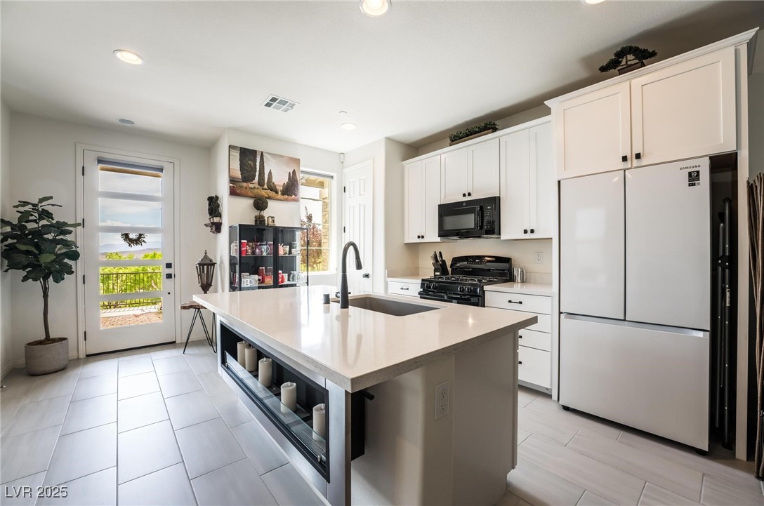 128 Kimberlite Drive Henderson, NV 89011 - Photo 13 of 55 Kitchen featuring black appliances, white cabinets, a kitchen island with sink, recessed lighting, and light stone counters