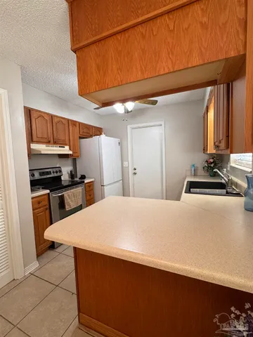 a kitchen with stainless steel appliances granite countertop a refrigerator a sink a stove and white cabinets