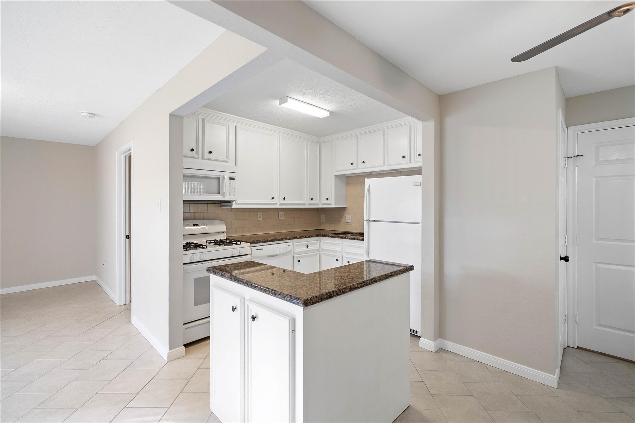 230 West 27th Street, Unit 3 Houston, TX 77008 - Photo 3 of 9 a kitchen with a stove a refrigerator and white cabinets