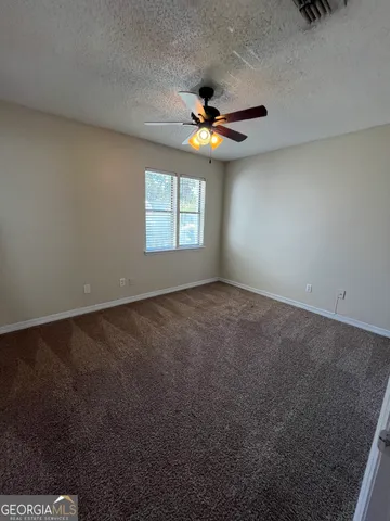 an empty room with windows and fan