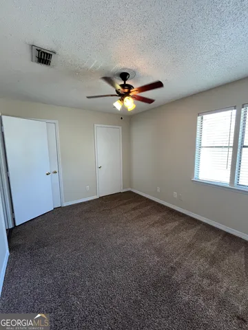 an empty room with windows and ceiling fan