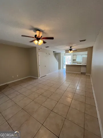 a view of an empty room and chandelier fan