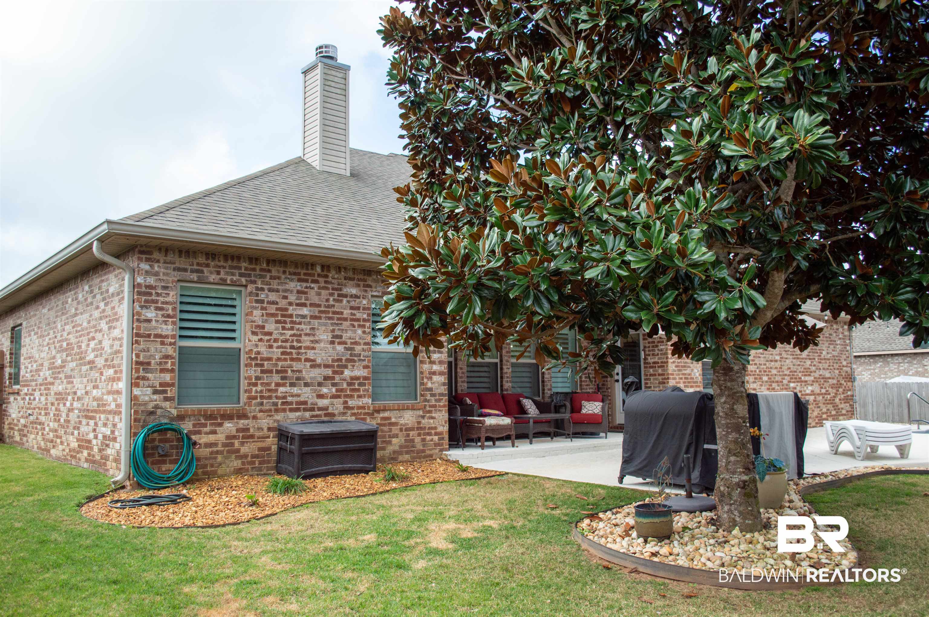 1124 West Orlando Drive Foley, AL 36535 - Photo 44 of 51 Rear view of house featuring a patio, brick siding, a yard, a chimney, and roof with shingles
