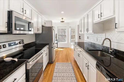 a kitchen with stainless steel appliances granite countertop a sink stove and refrigerator