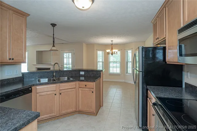 a kitchen with stainless steel appliances granite countertop a refrigerator a stove and a sink