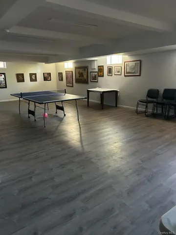 a living room with couches and pool table with wooden floor