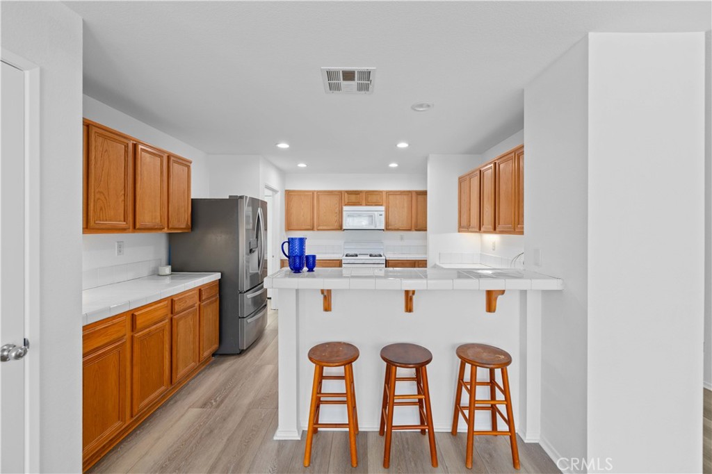 38133 Ranger Drive Palmdale, CA 93552 - Photo 10 of 29 a kitchen with stainless steel appliances a sink a stove a refrigerator cabinets and a dining table