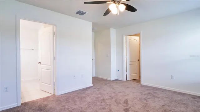 an empty room with a chandelier fan and windows