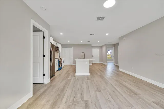 a view of a kitchen with a fridge and wooden floor