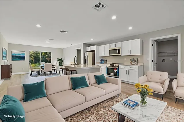 a living room with furniture white walls and kitchen view