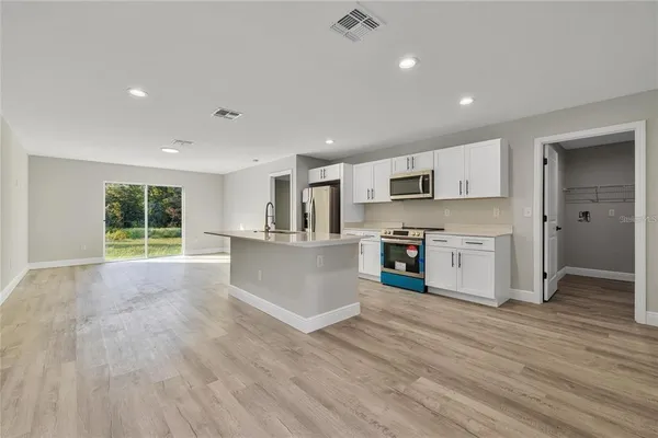 a view of kitchen with stainless steel appliances refrigerator oven and cabinets