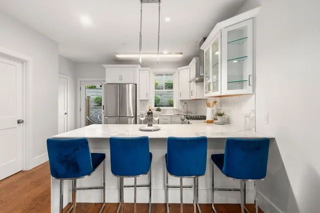 a kitchen with a dining table chairs sink and white cabinets