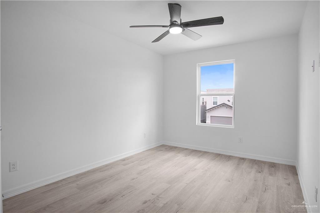 2310 Corales Street Mission, TX 78573 - Photo 13 of 23 an empty room with wooden floor ceiling fan and windows