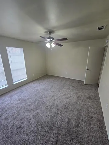 an empty room with windows and fan