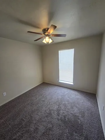 an empty room with a window and a ceiling fan