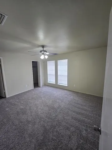 a view of a big room with windows and chandelier fan