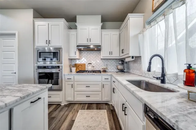 a kitchen with stainless steel appliances granite countertop a sink a stove and cabinets