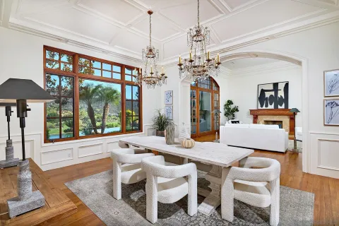 a dining room with wooden floor a chandelier a glass table and windows