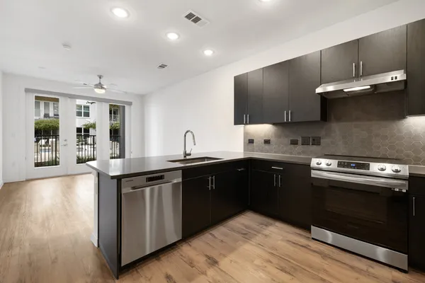 a kitchen with stainless steel appliances a sink dishwasher a stove and white cabinets with wooden floor