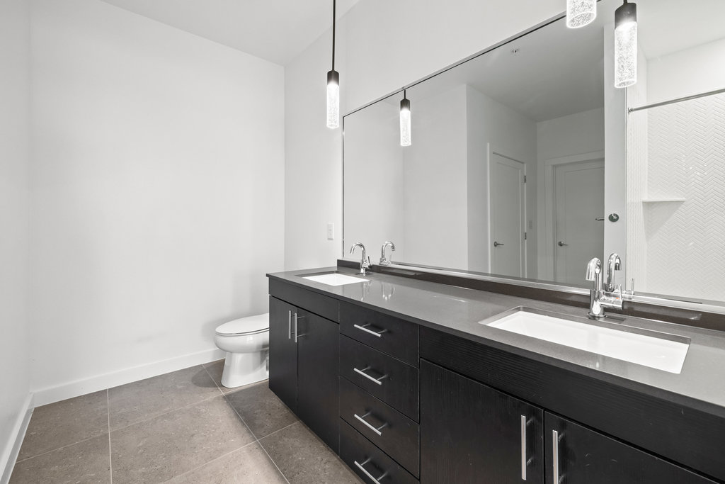 4801 Springdale Road, Unit 1106 Austin, TX 78723 - Photo 39 of 40 a bathroom with a granite countertop sink a toilet and a mirror