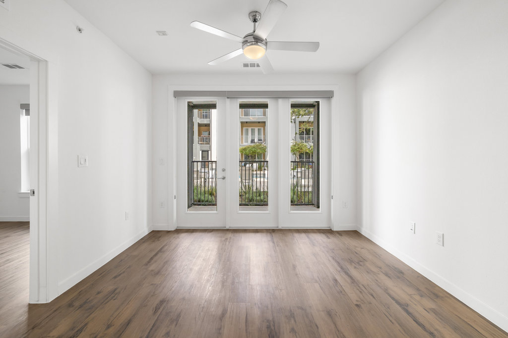 4801 Springdale Road, Unit 1106 Austin, TX 78723 - Photo 6 of 40 an empty room with wooden floor chandelier fan and windows