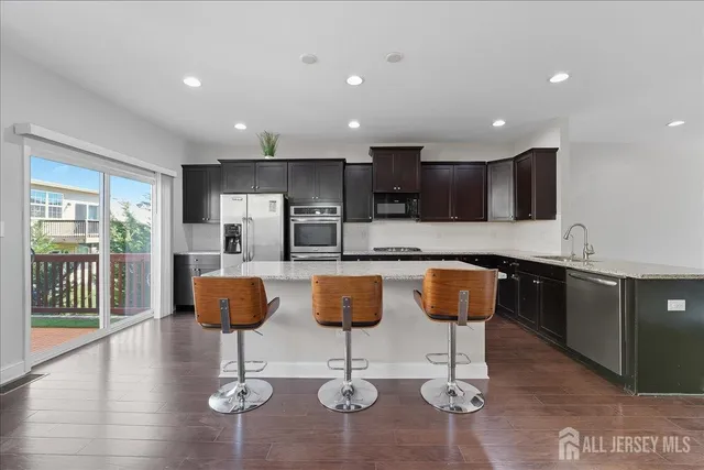 a kitchen with granite countertop kitchen island stainless steel appliances a sink a counter top space and a center island