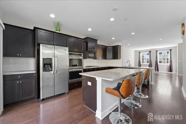 a kitchen with stainless steel appliances granite countertop a refrigerator a sink and a stove