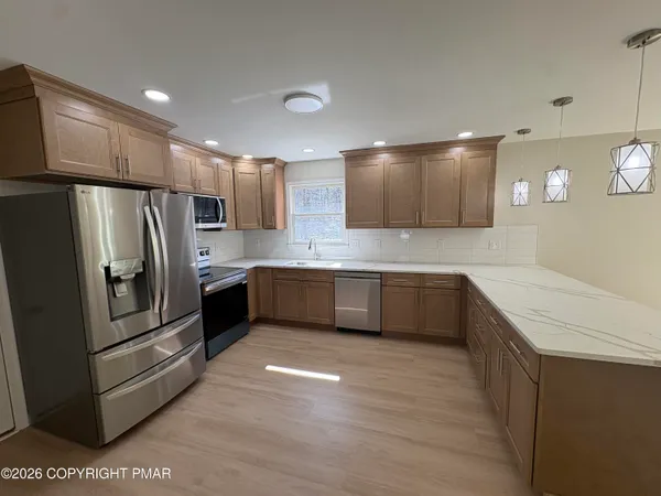 a kitchen with stainless steel appliances kitchen island granite countertop a refrigerator and a stove top oven