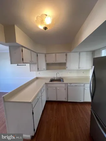 a kitchen that has a lot of cabinets in it and wooden floors