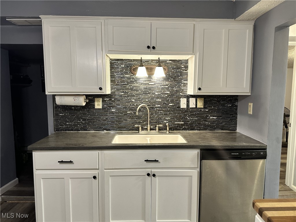 7700 Center Road Ashtabula, OH 44004 - Photo 6 of 31 Kitchen featuring dark countertops, dishwasher, a sink, and tasteful backsplash