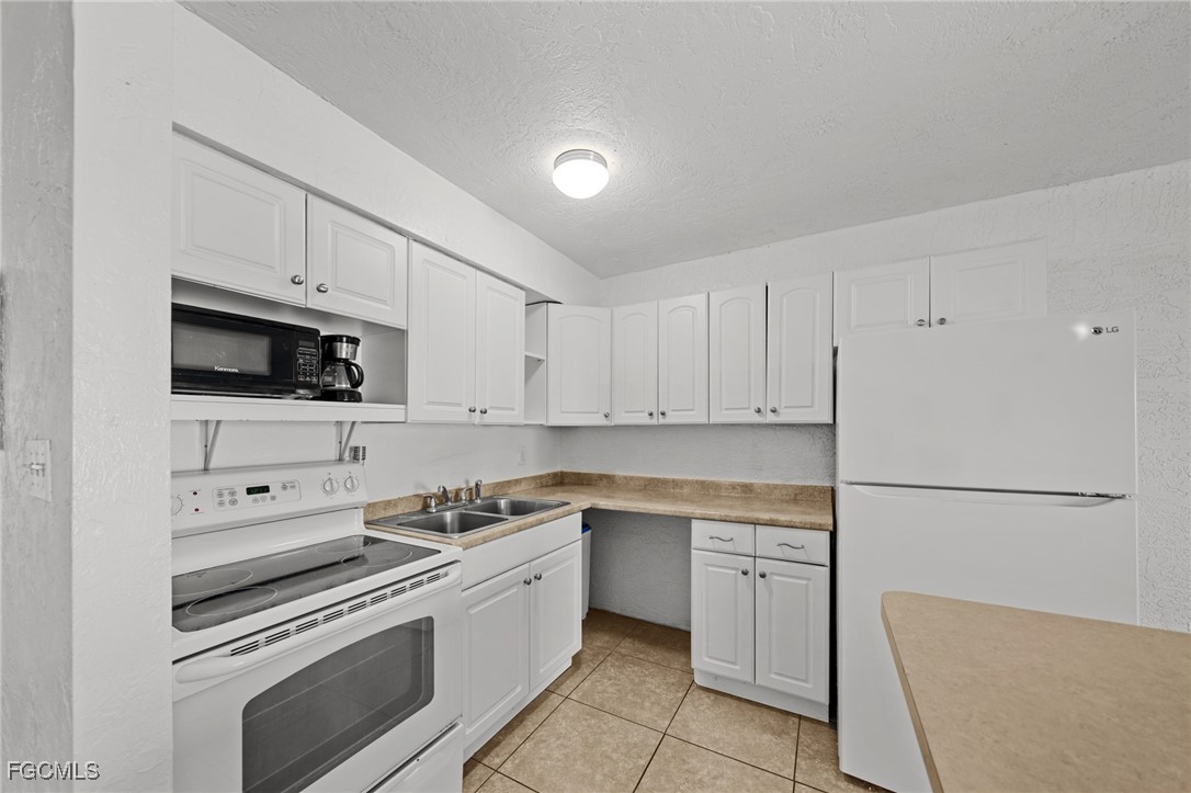 830 Wiggins Pass Road, Unit 14 Naples, FL 34110 - Photo 7 of 20 a kitchen with white cabinets and white appliances