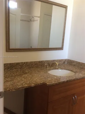 a bathroom with a granite countertop sink and a mirror